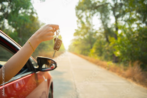Happy woman hand out window car red and car key with sunlight