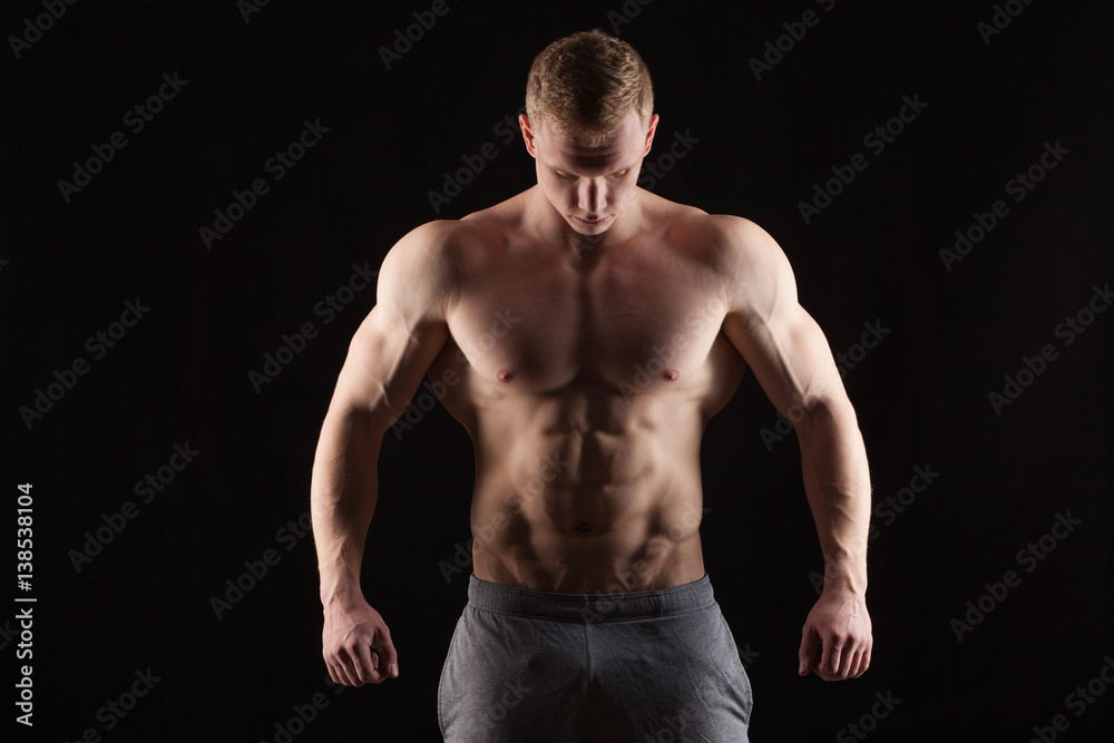 Athletic handsome man fitness-model showing six pack abs. isolated on black background with copyspace