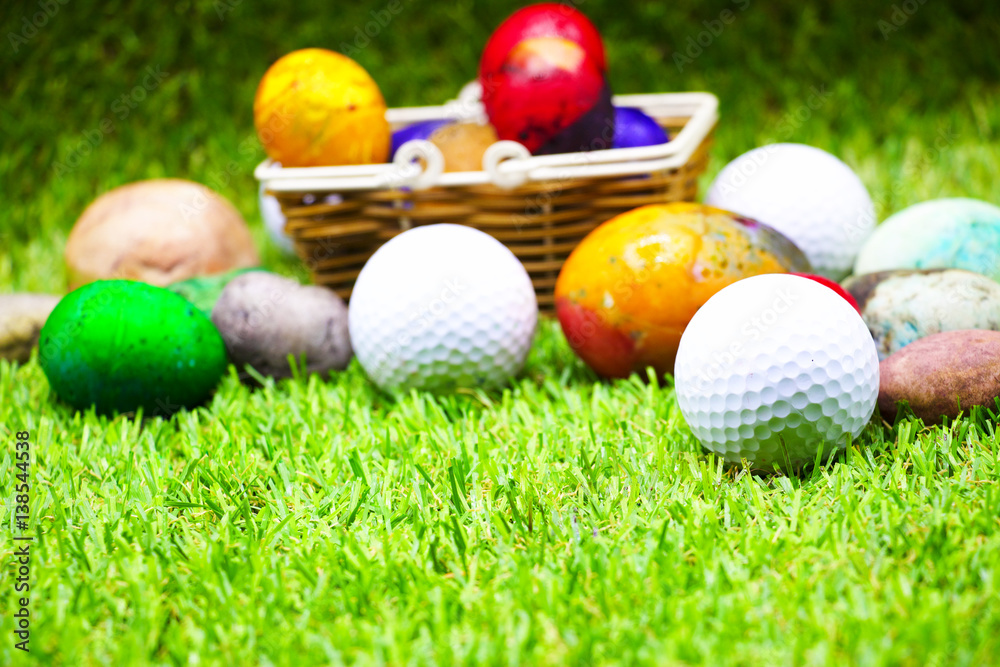 Golf balls with easter eggs are on green grass. Stock Photo Adobe Stock