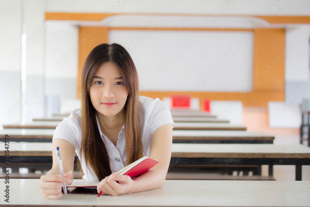 Portrait of thai adult student university uniform beautiful girl reading red book Portrait of thai adult student university uniform beautiful girl reading red book