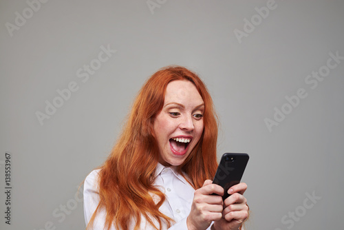 Joyful red hair girl using mobile phone