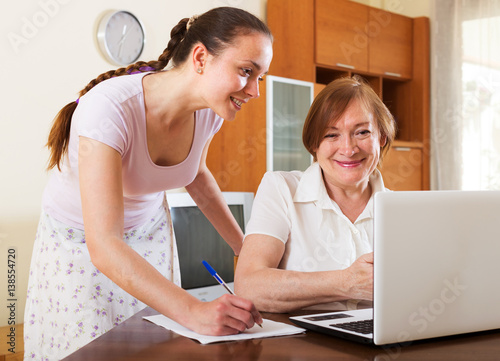 Happy women looking financial documents in laptop