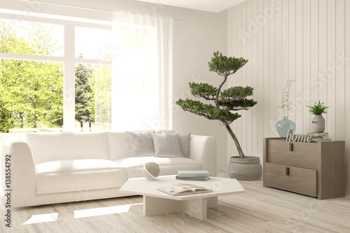 White room with sofa and green landscape in window. Scandinavian interior design