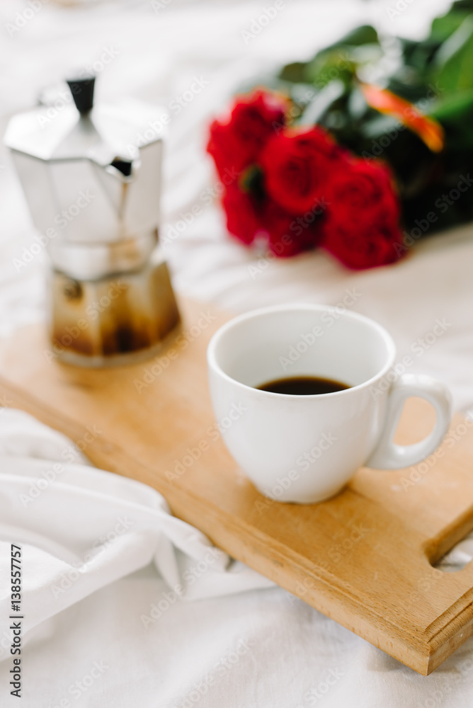 A cup of coffee, coffee on the wooden Boards, a bouquet of red roses on a white background A cup of coffee, coffee on the wooden Boards, a bouquet of red roses on a white background