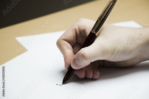 Close up of a man's hand writing signature on paper document - business concept