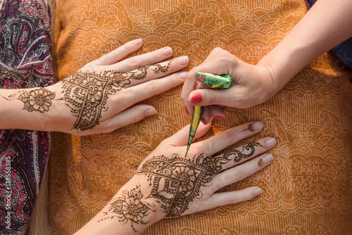 Drawing Mehndi henna tattoo on women hands photo