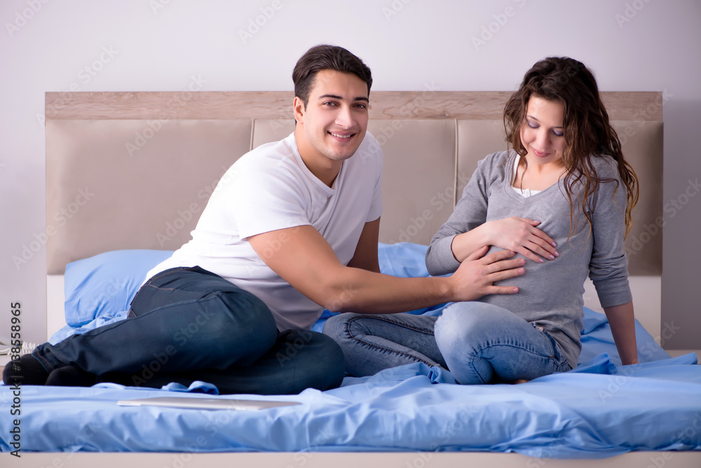 Young family with pregnant wife expecting baby in bed Young family with pregnant wife expecting baby in bed