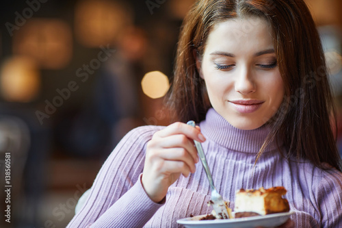 Beautiful woman eating chocolate cake at cafe