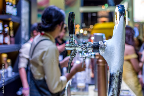 Barman or bartender pouring a beer from beer tap