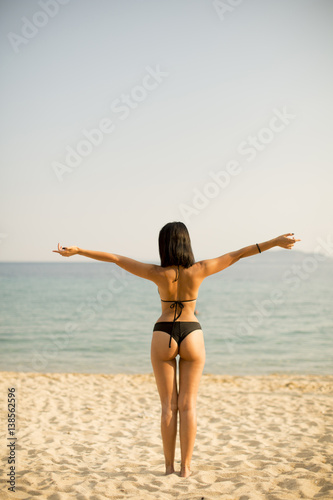 Young woman standing on the beach in a bikini