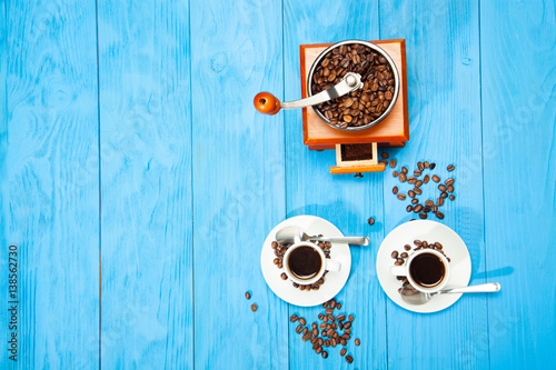 Two cup of coffee and grinder on a wooden blue background photo