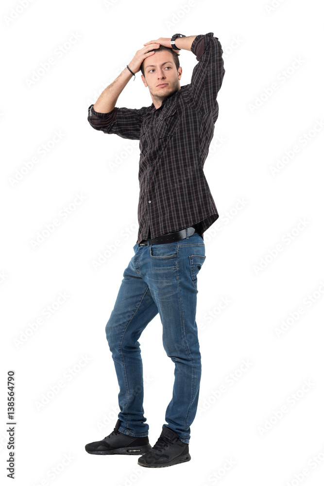 Young handsome man in jeans and plaid shirt with hands on head posture. Full body length portrait isolated over white background. Young handsome man in jeans and plaid shirt with hands on head posture. Full body length portrait isolated over white background.