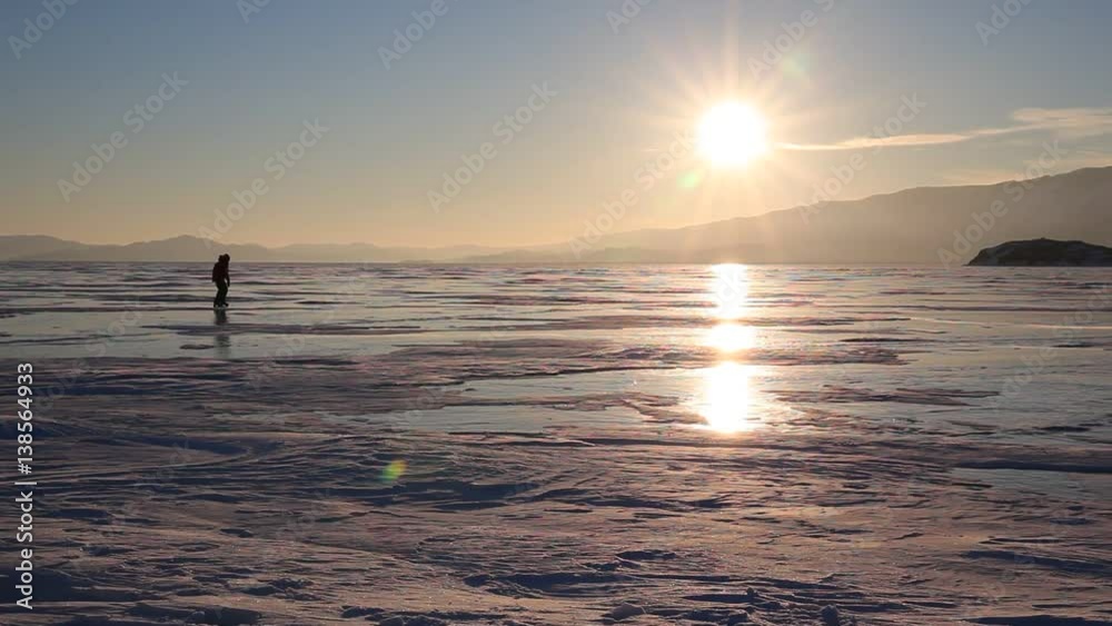 People skating on the ice of lake Baikal at sunset People skating on the ice of lake Baikal at sunset