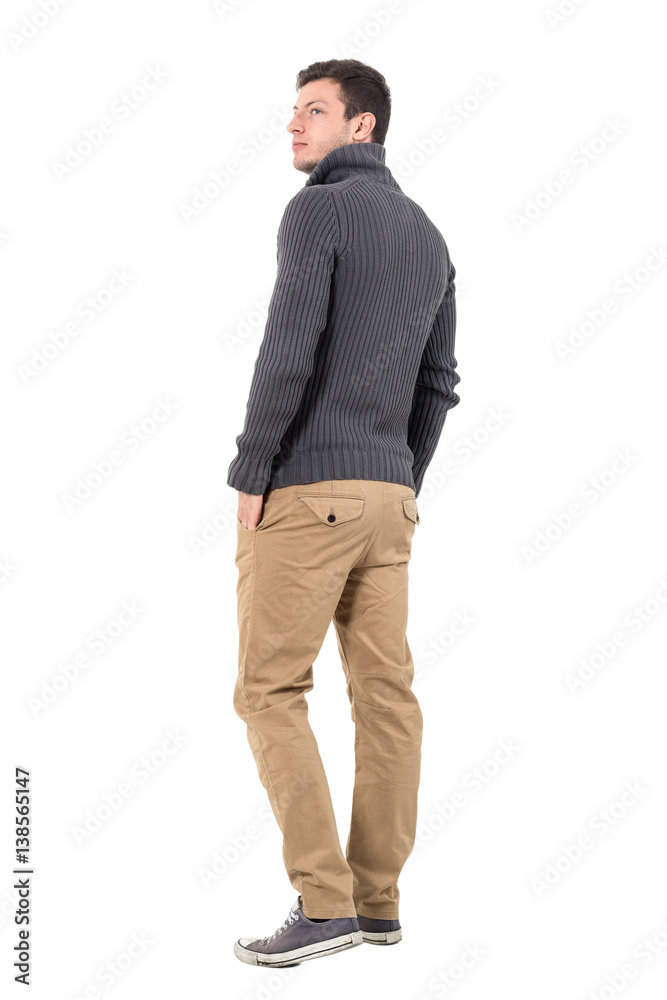 Rear view of young casual man in gray sweater looking up over shoulder. Full body length portrait isolated over white background. Rear view of young casual man in gray sweater looking up over shoulder. Full body length portrait isolated over white background.