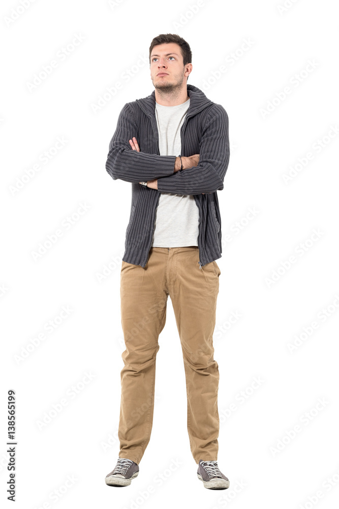 Confident casual man with crossed arms looking up wearing gray zip sweater. Full body length portrait isolated over white background. Confident casual man with crossed arms looking up wearing gray zip sweater. Full body length portrait isolated over white background.