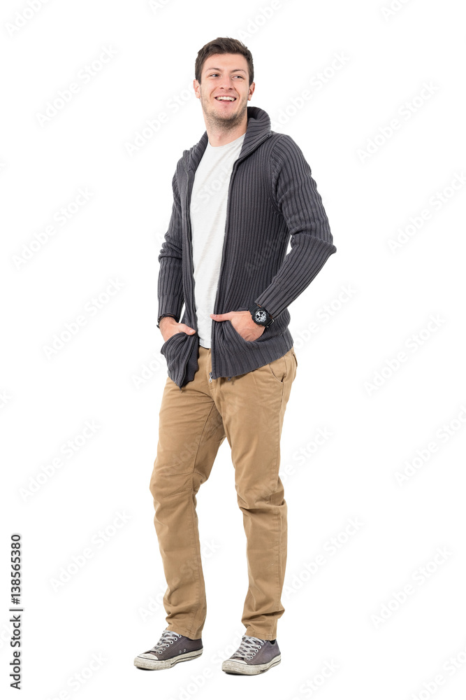Happy smiling casual man wearing sweater jacket with hands in pockets looking back. Full body length portrait isolated over white background. Happy smiling casual man wearing sweater jacket with hands in pockets looking back. Full body length portrait isolated over white background.