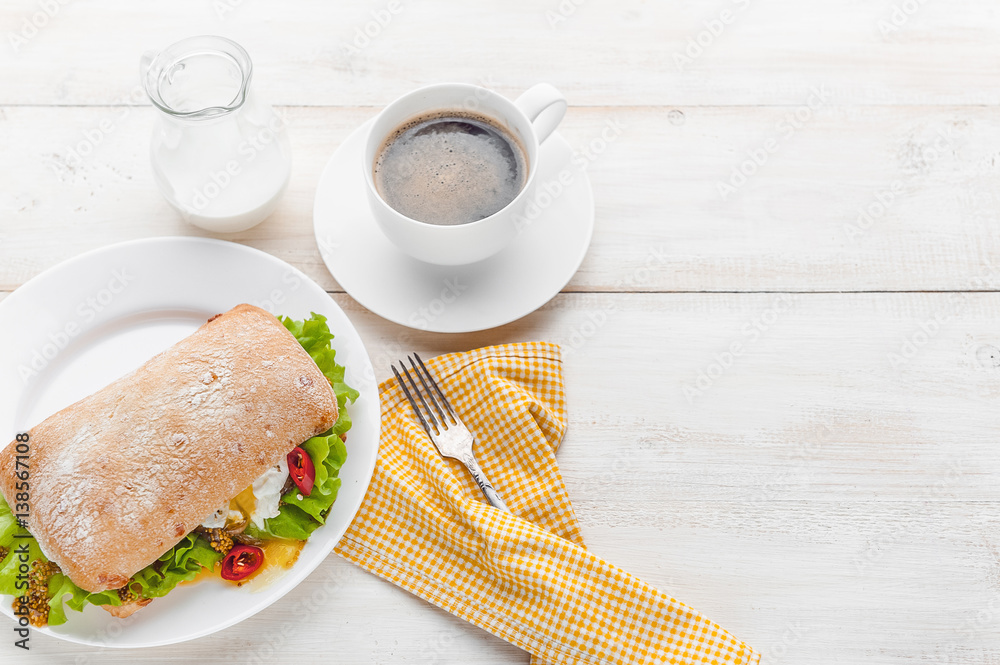 breakfast in a rustic style on a white wooden surface. ciabatta with poached egg and grain mustard with a hot cup of coffee and fresh breakfast in a rustic style on a white wooden surface. ciabatta with poached egg and grain mustard with a hot cup of coffee and fresh