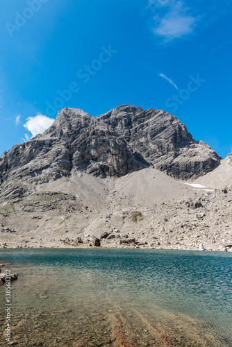 Melt water lake below a high rocky alpine peak