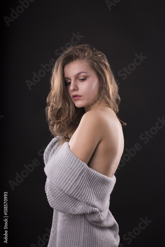 Fashionable young woman posing in sweater with naked shoulders
