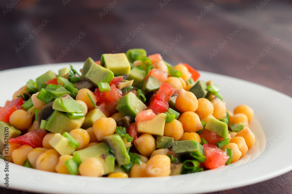 Healthy salad. Chickpea, tomato and avocado with olive oil. Closeup food photo.
