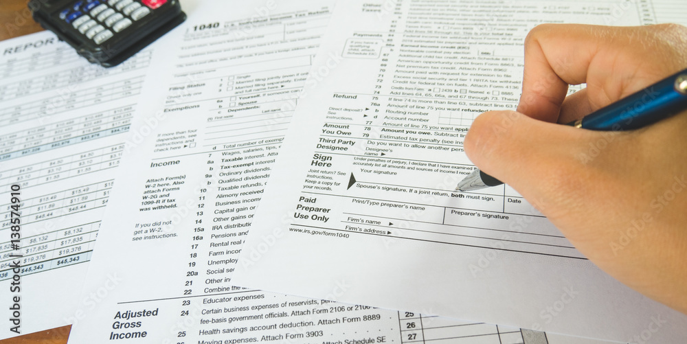 Hand hold pen on sign point on the tax forms paper in business concept Hand hold pen on sign point on the tax forms paper in business concept