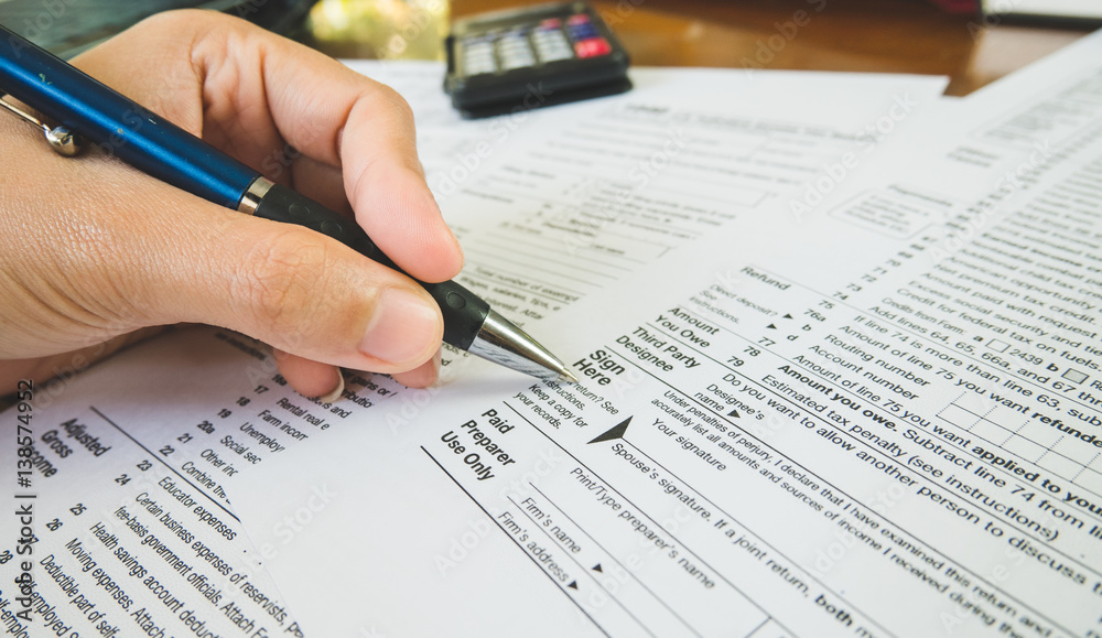 Hand hold pen on sign point on the tax forms paper in business concept
