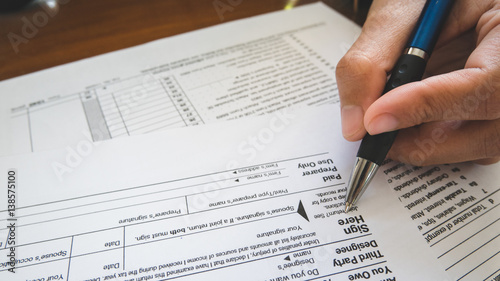 Hand hold pen on sign point on the tax forms paper in business concept