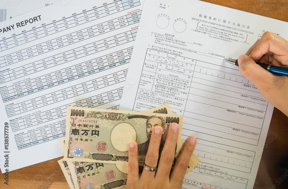 Obraz premium Woman hand hold pen fill in the details on the tax forms paper with yen moneyin business concept.