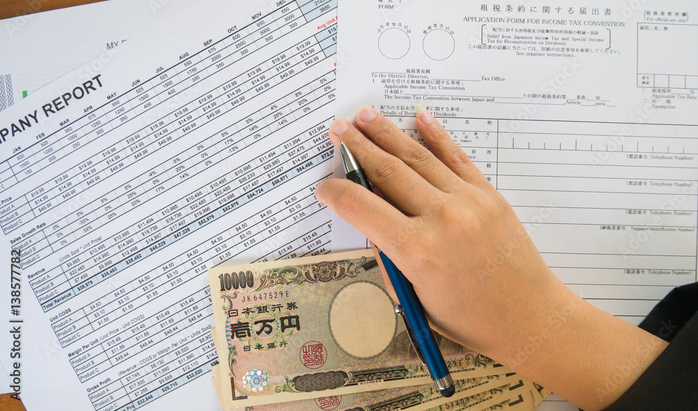 Obraz premium Woman hand hold pen fill in the details on the tax forms paper with yen moneyin business concept.