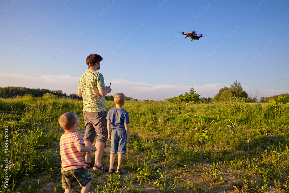 Fototapeta premium Ojciec i syn sterują dronem RC na niebie