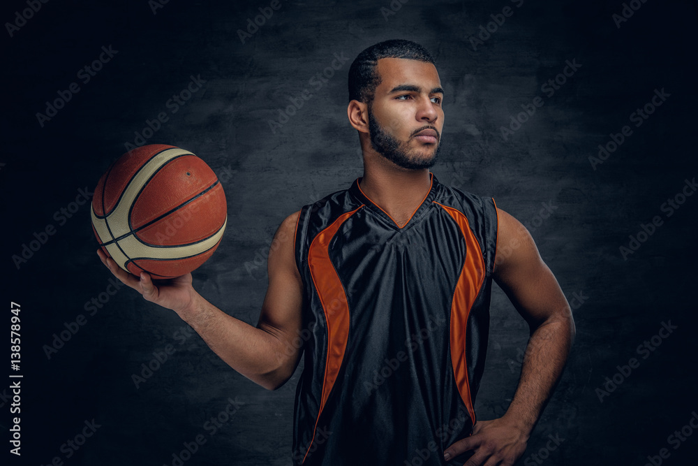 Basketball player holds a ball over grey background. Basketball player holds a ball over grey background.