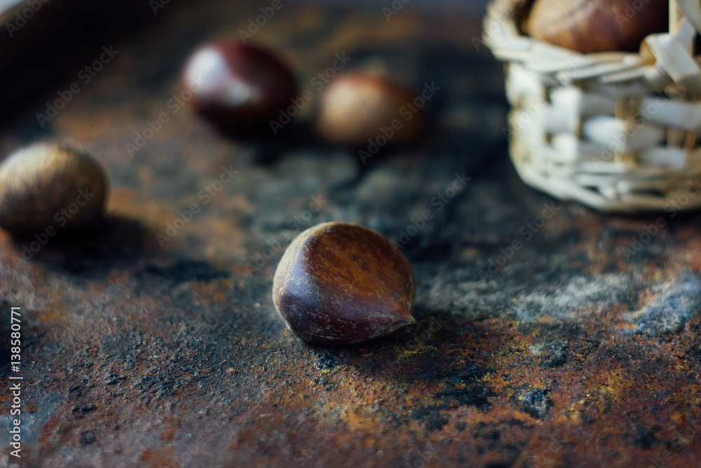 Fresh chestnuts in basket over black rustic surface.
