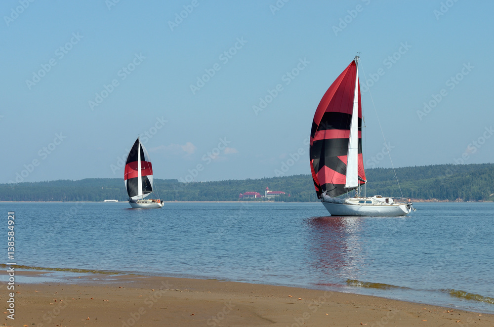 Fototapeta premium Sailing boats on the river, the reflection on water in the distance shore.
