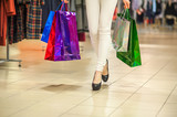 Girls and shopping, slender legs of a girl with shopping bags in a boutique or mall