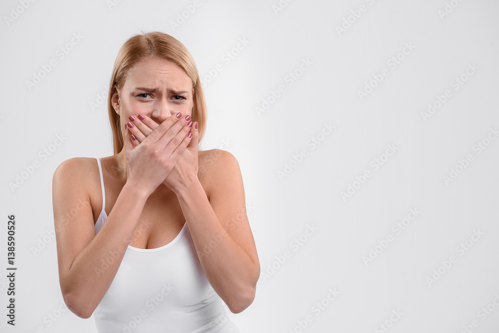 Nervous young woman closing mouth with shame Nervous young woman closing mouth with shame