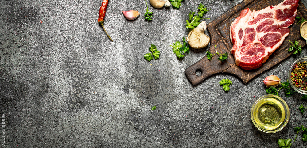 Raw meat background. A piece of Raw pork chops with fragrant spices and fresh herbs. On rustic background. Raw meat background. A piece of Raw pork chops with fragrant spices and fresh herbs. On rustic background.