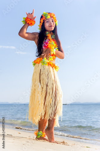 Hula Hawaii dancer dancing on the beach with horizon of sea. Ethnic woman in costume dancer Hawaii hula dancing in a tropical island.