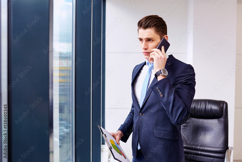 Brunet businessman talking on the phone in a business office. Brunet businessman talking on the phone in a business office.