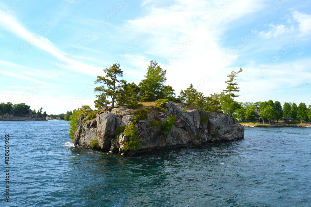 1000 Islands Region. Sunny summer day. Rocky Island on the St. Lawrence River crowned with pine trees. Kingston, Ontario, Canada. Unfiltered, natural lighting. Tourist routs.
