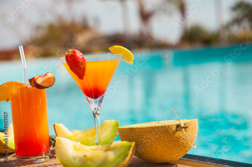 Cold cocktail near the pool in summer time with strawberry and orange