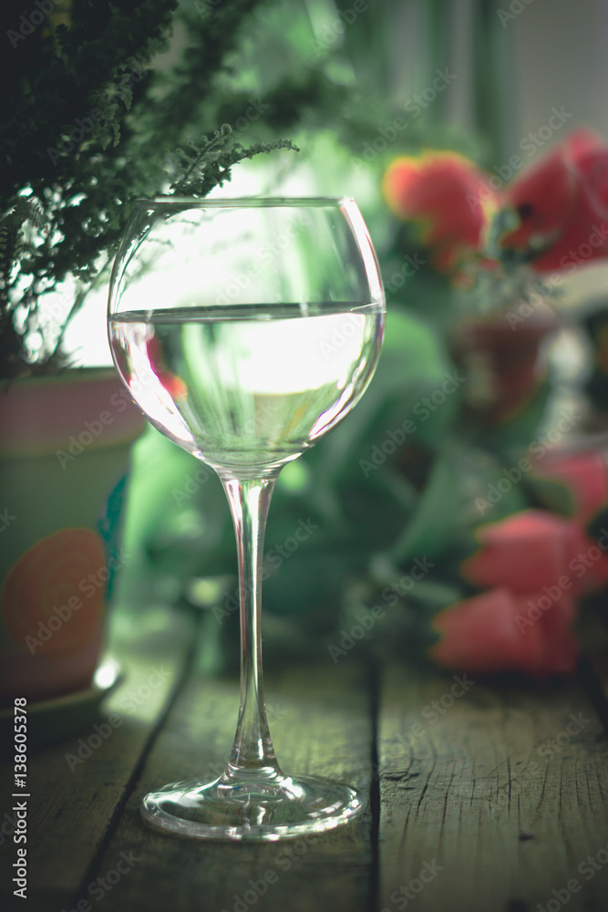 A glass of water on the flowers and plants against A glass of water on the flowers and plants against