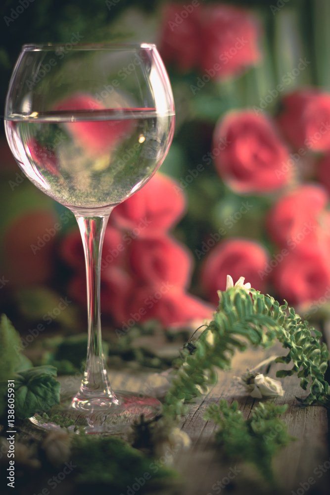 A glass of water on the flowers and plants against A glass of water on the flowers and plants against