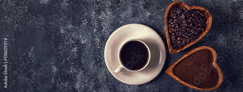 Coffee cup, beans and ground powder on stone background. 