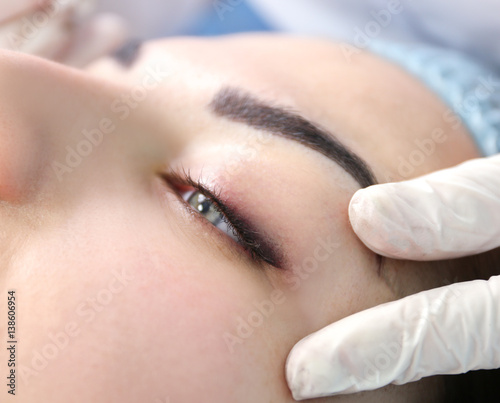 Young beautiful woman making permanent makeup in cosmetology salon photo