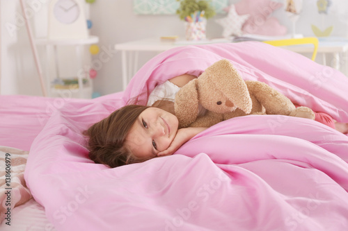 Cute little girl lying in b...