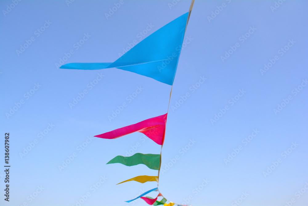 Triangle flags hanging on the rope against the blue sky