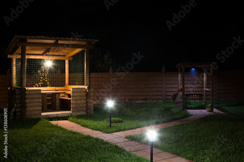 arbor and barbecue in backyard at night