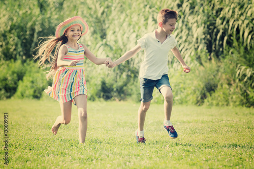 Two children running in park.