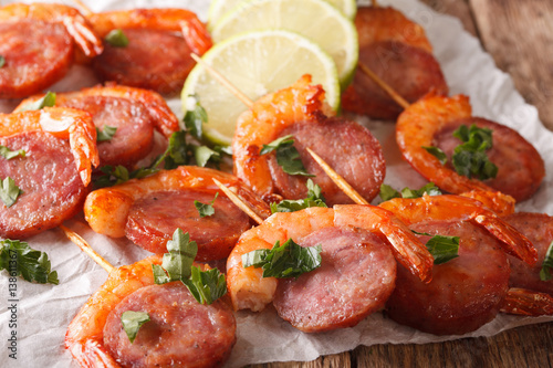 Baked shrimp and chorizo on skewers with fresh herbs close up. horizontal © FomaA
