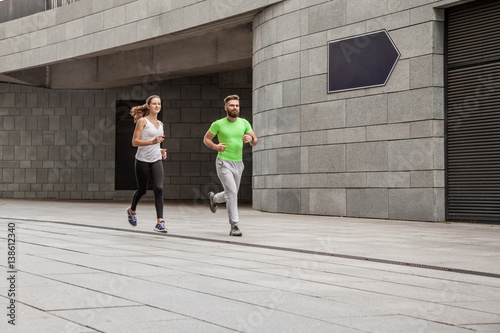 Side view of couple running in an urban environment.